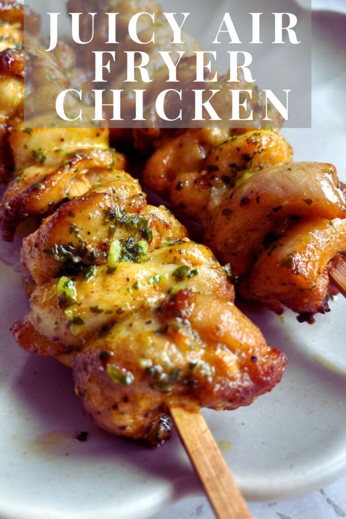 Two grilled chicken skewers garnished with garlic herb butter on a white ceramic plate, displaying a golden-brown color with visible grill marks.