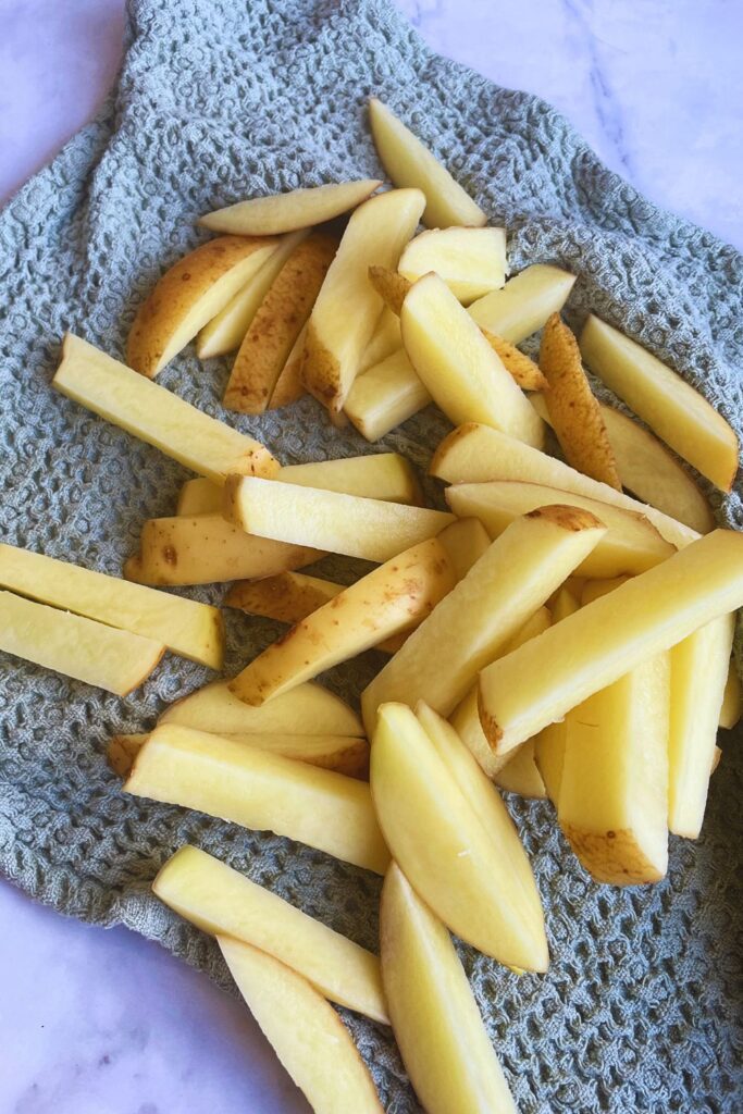 Potatoes cut for making fries laid in a green towel
