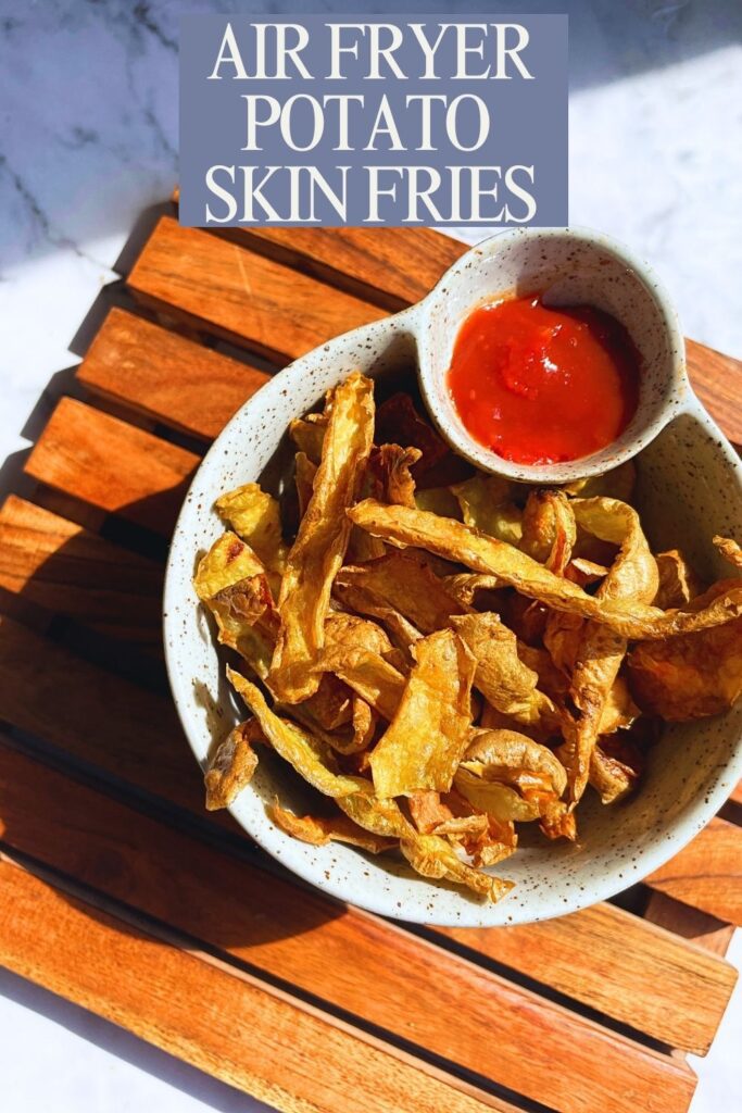 a bowl of air fryer potato skin fries with sauce on side served on a wooden board