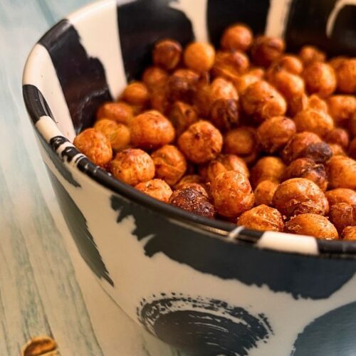 A bowl of air fried chickpea snacks on a wooden surface