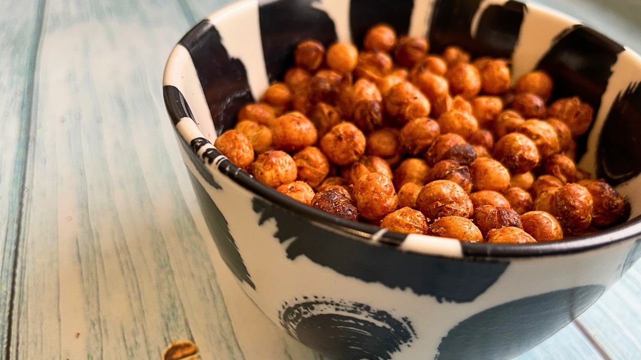 A bowl of air fried chickpea snacks on a wooden surface