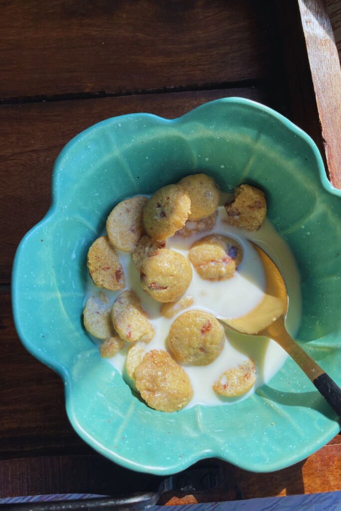 Homemade Cookie crisp cereal served on a blue bowl with milk and a spoon