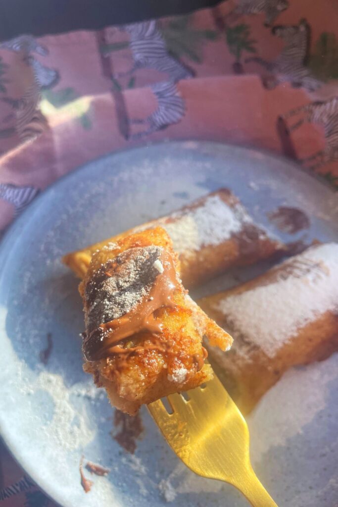 Close up shot of Nutella French Toast Rolls on a golden fork and 2 served in a plate