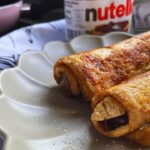 2 Nutella French Toast Rolls served in a grey plate and a nutella jar at the back