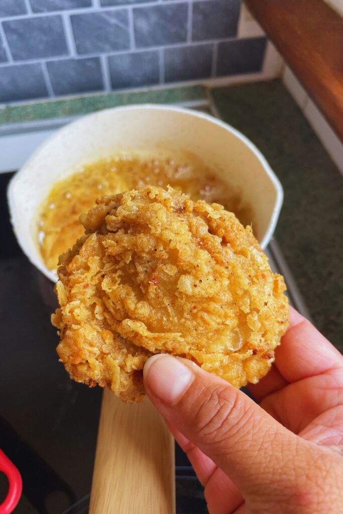 A hand holding freshly made crispy Fried Chicken