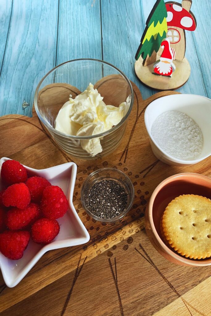 Party Appetisers Raspberry & Cream Cheese Crackers Ingredients cream cheese, icing sugar, ritz crackers, fresh raspberries and chia seeds laid on a wooden board