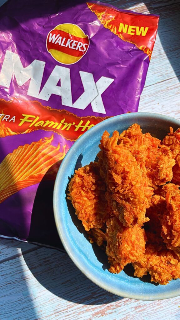 Freshly air fried walkers crispy chicken bites served in a blue bowl with a walkers crisp packet behind