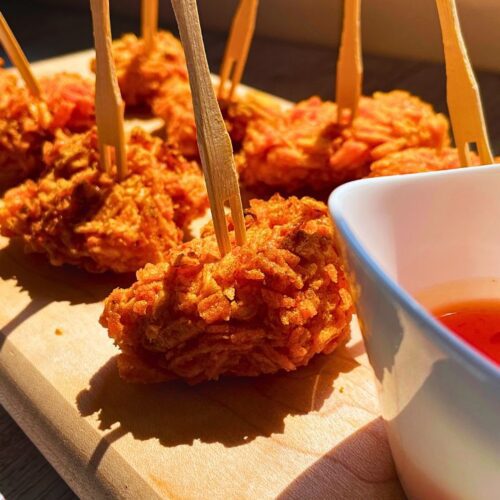 Walkers crispy chicken bites in air fryer served on a wooden board with some sauce