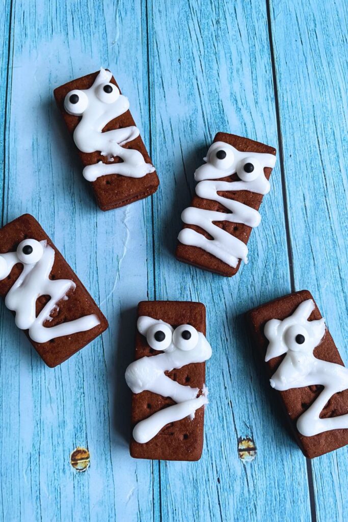 5 spooky Halloween Mummy Biscuits laid on a blue table